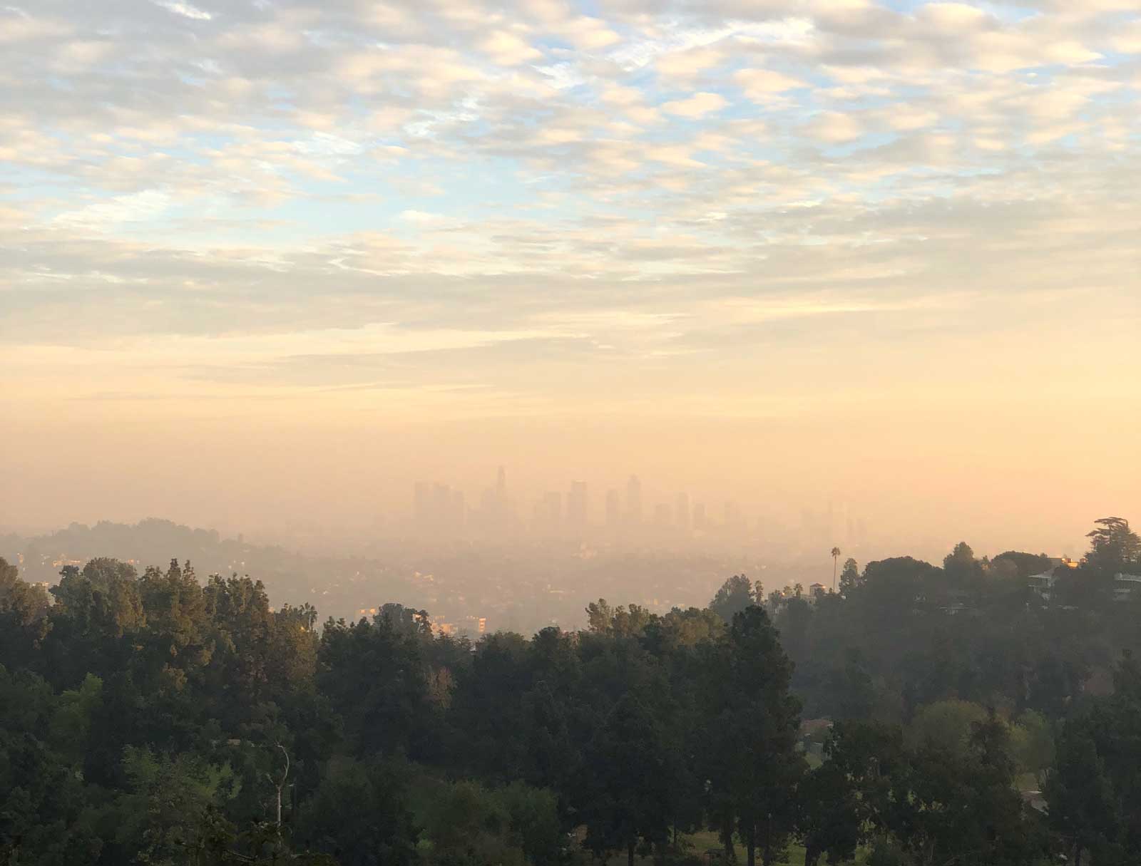 Picture of a foggy/smoggy sunset where you can barely make out a skyline of downtown Los Angeles