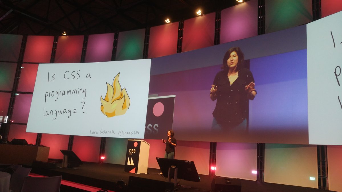 Lara giving a talk on a big stage, with a slide that says "Is CSS a programming language?"