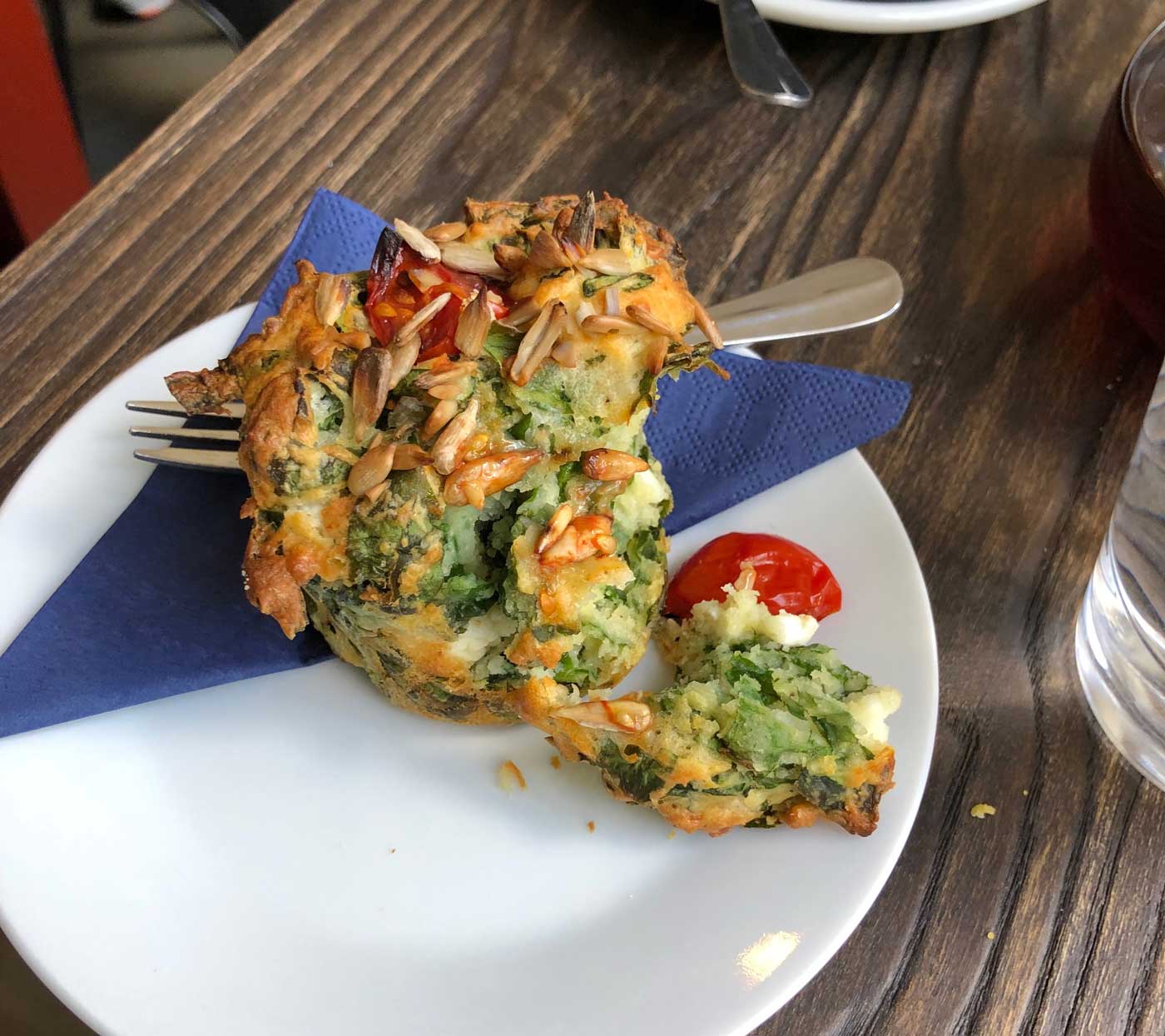 A very delicious looking muffin with spinach inside the dough and a visible tomato
