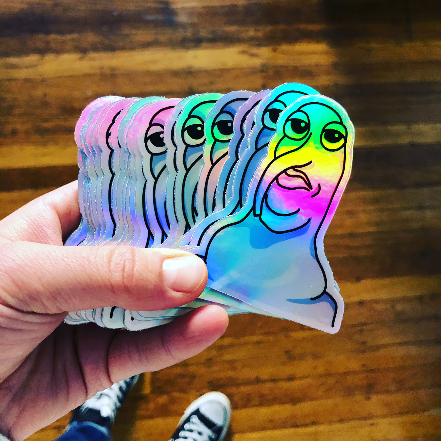 A hand holding a set of holographic monster stickers