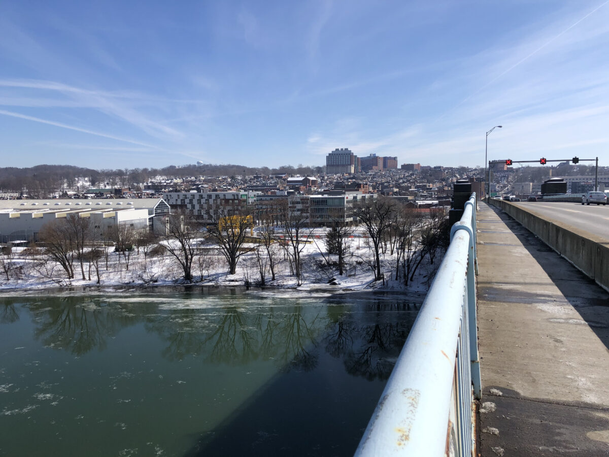 A photo of a clear sky from a bridge over the river and a town