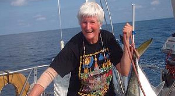 A woman with short white hair and sunburnt white skin on a sail boat